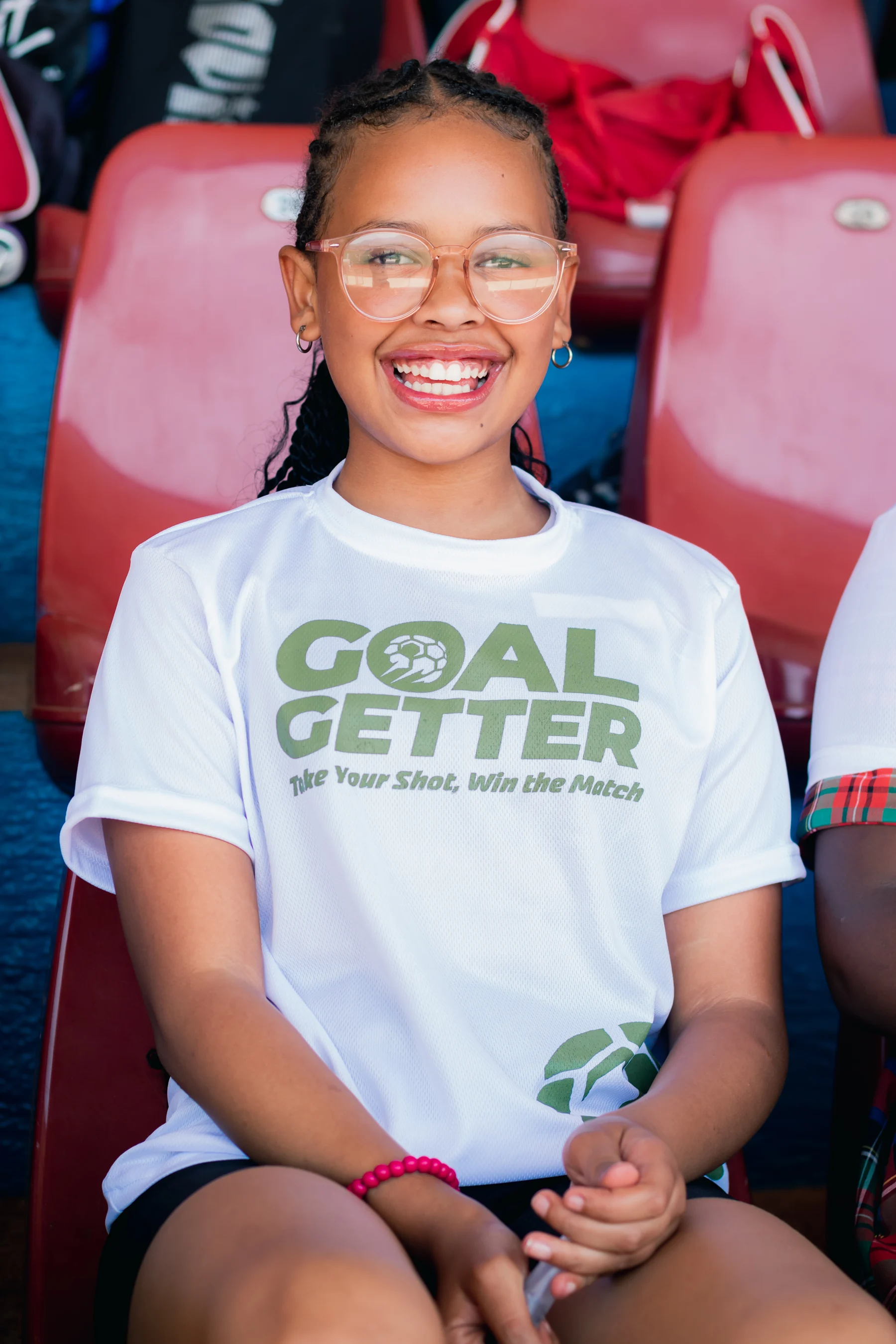 A young participant wearing the Goal Getters shirt in the stadium stands